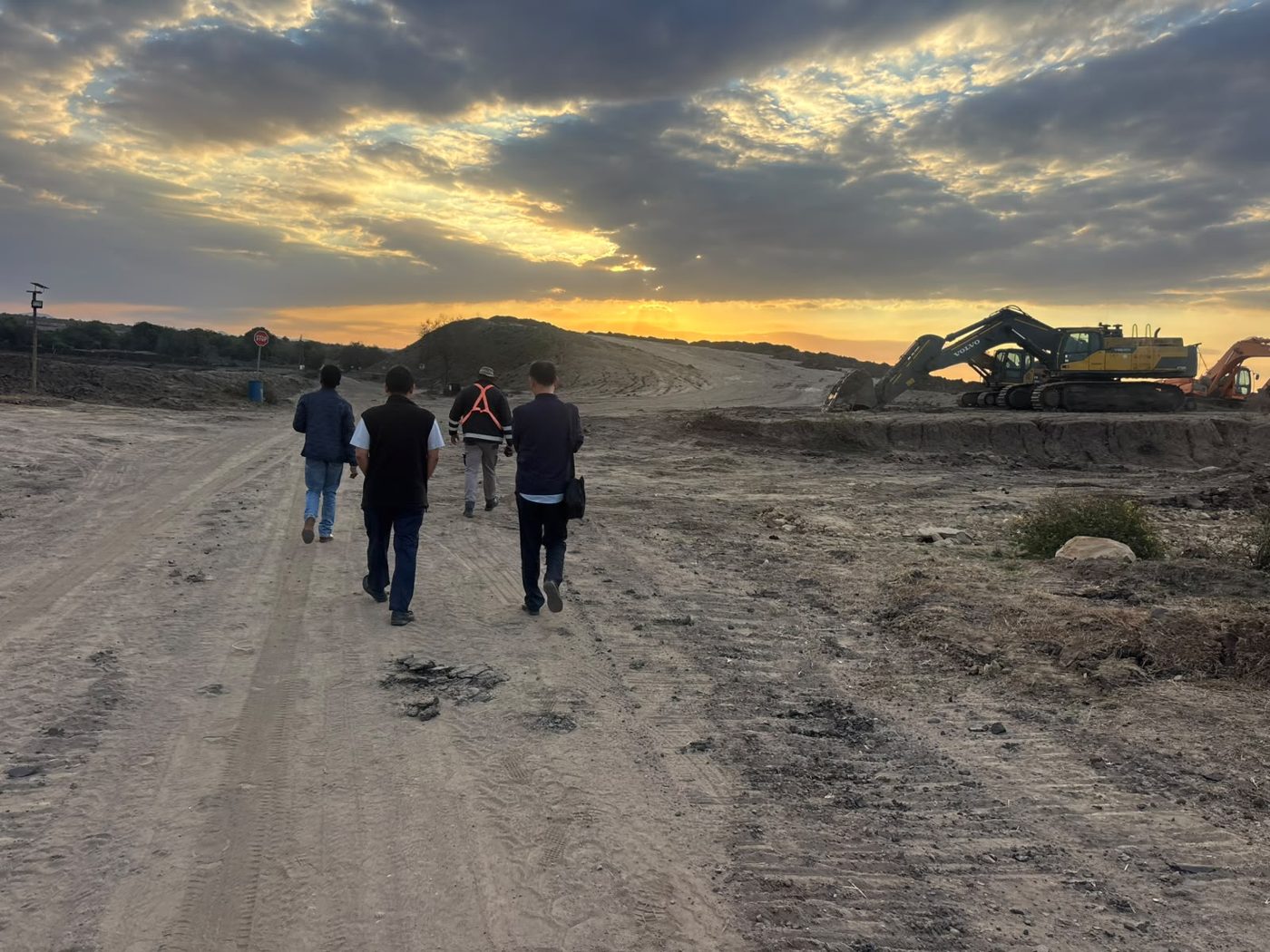 SVT Group team walking a haul road at sunrise with excavators working on the mining site