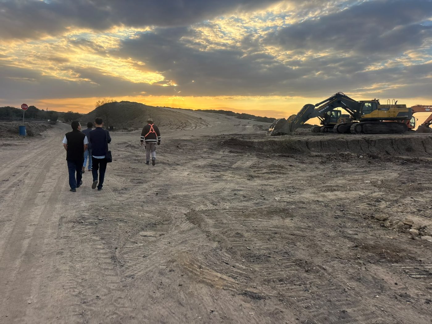 Site inspection team on a mining haul road with a Volvo excavator on the bench